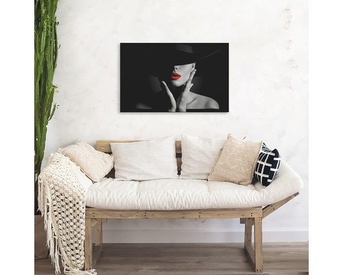 Pictură murală cu o femeie cu pălărie și ruj roșu deasupra unei canapele.