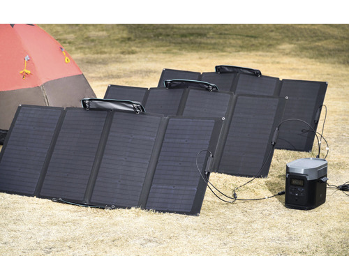 Mai multe panouri solare pe sol cu centrală electrică portabilă și cort în fundal