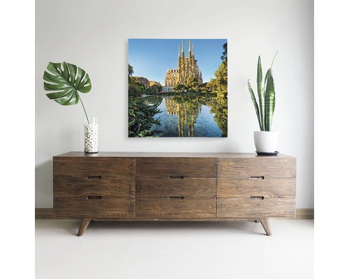 Imagine decorativă cu Sagrada Familia deasupra unei comode din lemn cu plante