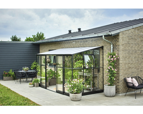 Seră de sticlă cu plante lângă o casă și o terasă