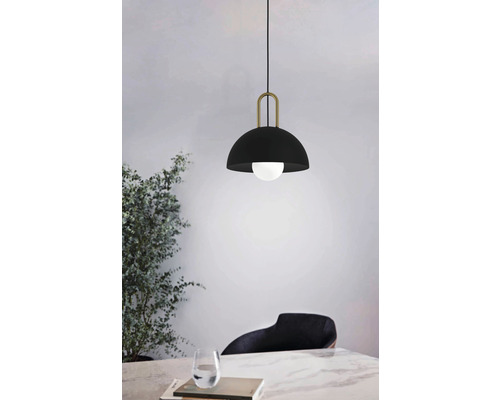 Lumină suspendată cu abajur negru și suspensie aurie deasupra unei mese