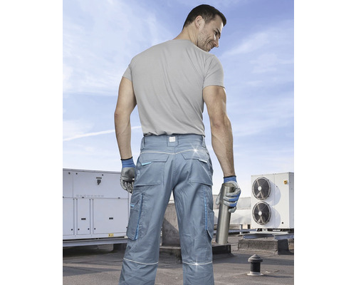 Bărbat cu pantaloni de lucru și mănuși de lucru pe un acoperiș