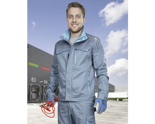 Bărbat în haine de lucru cu cabluri de pornire în fața unui depozit