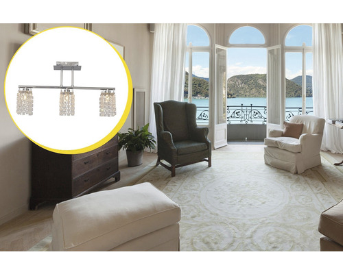 Cameră de zi cu lustră, fotolii și ușă de terasă deschisă cu vedere la un lac.