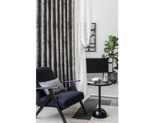 Cameră de zi cu fotoliu, perdele, masă și plantă de apartament