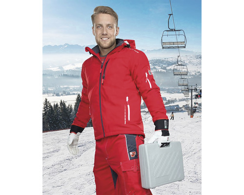Bărbat în haine de lucru roșii cu cutie de scule pe o pârtie de schi