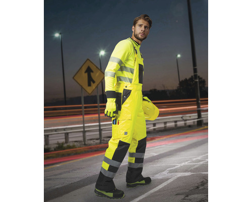 Bărbat în îmbrăcăminte de lucru cu vizibilitate ridicată pe un drum
