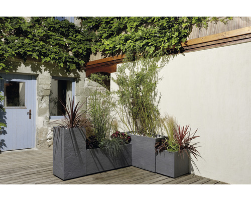 Trei jardiniere gri din gresie cu plante în exterior.