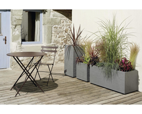Scenă de grădină cu masă, scaun și jardiniere plantate pe o terasă
