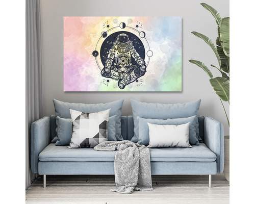 Tablou pe pânză cu un astronaut în poziție de meditație în fața unui fundal de mandala deasupra unei canapele