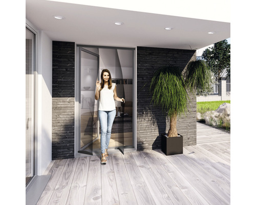 O femeie intră într-o casă modernă cu ușă glisantă și terasă din lemn