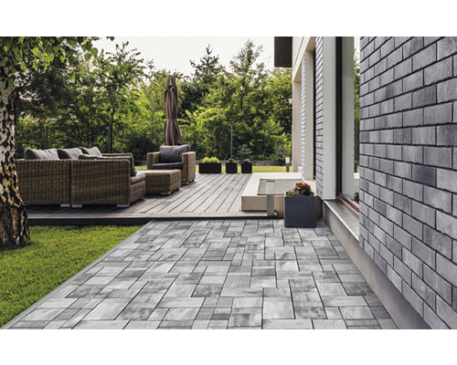 Spațiu exterior cu mobilier de grădină pe o terasă cu pavaj și un gazon adiacent