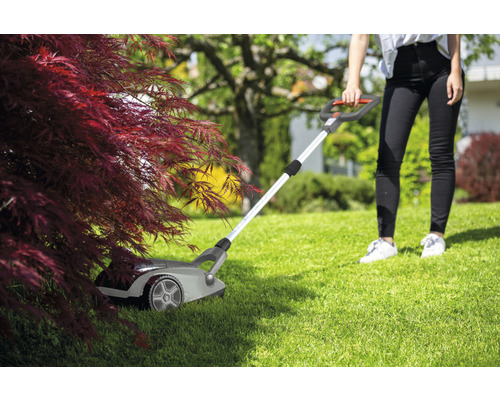 Scena cu o femeie care tunde iarba cu o mașină de tuns iarba