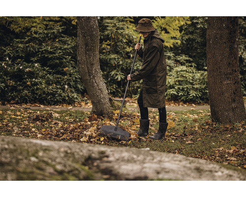 O persoană mătură frunzele cu o greblă în grădină.