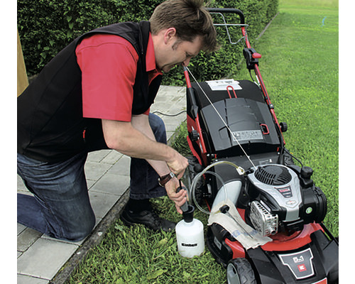 Un bărbat toarnă ulei într-o mașină de tuns iarba