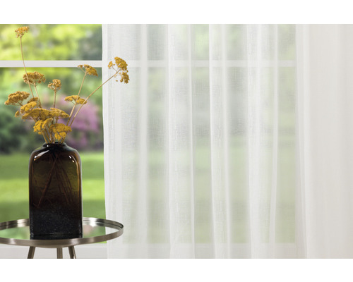 Perdea albă, transparentă, în fața unei ferestre cu o vază de flori pe o masă