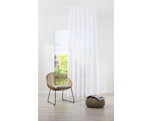 Cameră de zi cu fereastră, perdea albă, fotoliu din ratan și puf