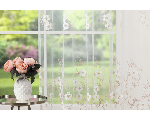 Perdea decorativă albă cu model floral în fața unei ferestre