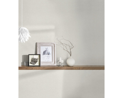 Scenă de living cu tapet deschis la culoare, raft, obiecte decorative și lampă
