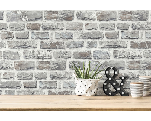 Tapetă decorativă cu aspect de piatră pe un perete cu plantă, semn decorativ & și cutii decorative pe o masă