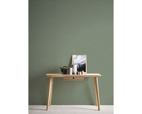 Masa din lemn cu decoratiuni in fata unui perete verde