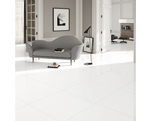 Cameră luminoasă cu gresie albă lucioasă, canapea și lampă de podea