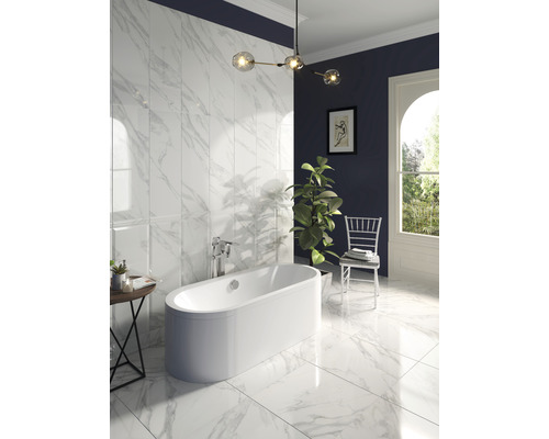 Baie modernă cu cadă independentă, gresie și faianță cu aspect de marmură și iluminat decorativ.