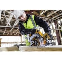 Un muncitor în construcții folosește un fierăstrău circular portabil DeWalt pentru a tăia lemn.