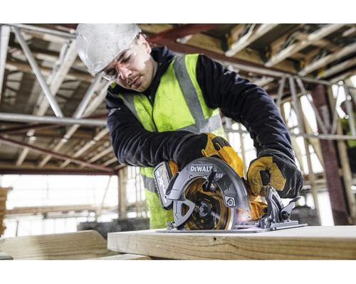 Un muncitor în construcții folosește un fierăstrău circular portabil DeWalt pentru a tăia lemn.