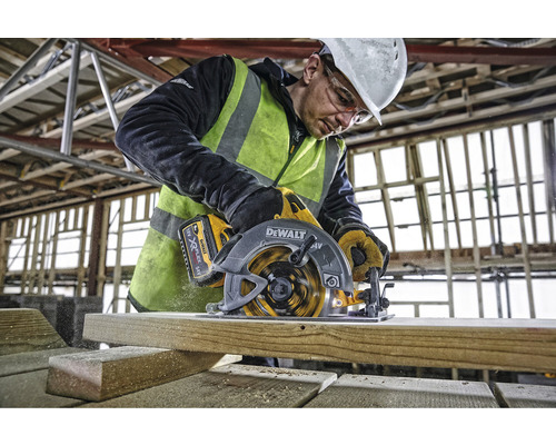 Un muncitor taie o scândură de lemn cu un ferăstrău circular DeWalt.