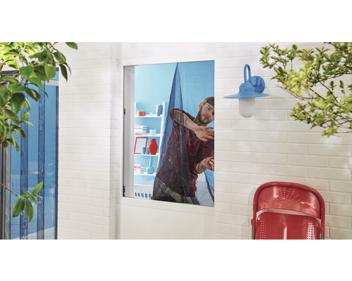 Un bărbat montează o plasă de țânțari pe o fereastră pentru protecție împotriva insectelor.