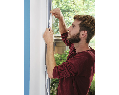 Bărbat aplică bandă de etanșare pe fereastră