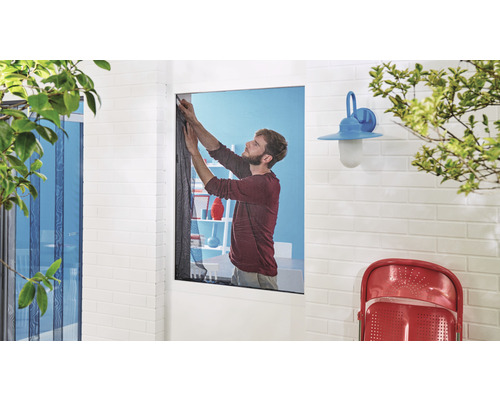 Bărbat care fixează o plasă de țânțari pe o fereastră.