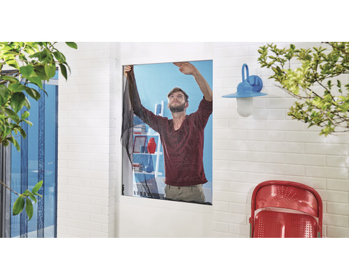 Un bărbat montează o plasă de țânțari la o fereastră pentru a împiedica intrarea insectelor.