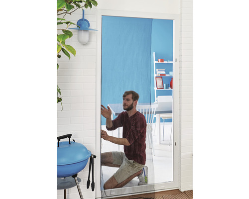 Un bărbat instalează o plasă de insecte pe o ușă. În fundal se văd un grătar și mobilier de grădină.