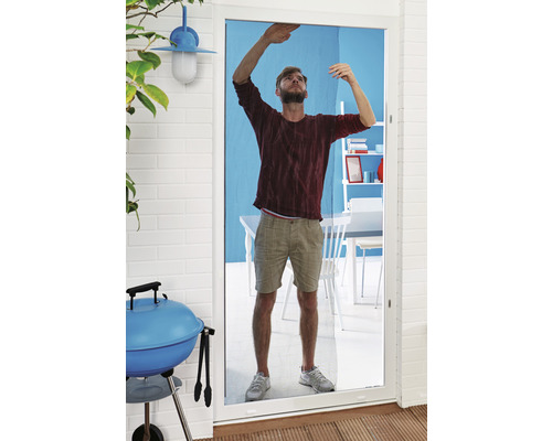 Un bărbat instalează o plasă de insecte pe o ușă de terasă.