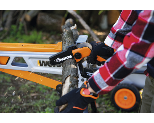 O persoană folosește un ferăstrău electric fără fir Worx pentru a tăia o ramură pe un capră de tăiat lemne.