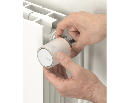 Persoană care instalează un termostat Netatmo pe un radiator.