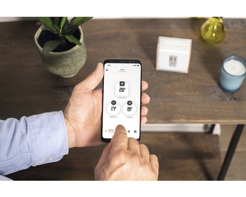 Un bărbat operează o aplicație Smart Home pe un smartphone pentru a regla temperatura.