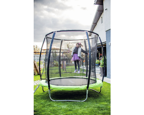 Fată sărind pe o trambulină de grădină cu plasă de siguranță