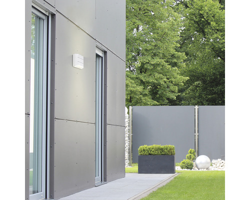 Aspect exterior al unei case moderne cu corp de iluminat exterior, ferestre glisante și amenajare peisagistică