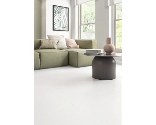 Living cu canapea verde, masă și gresie albă.