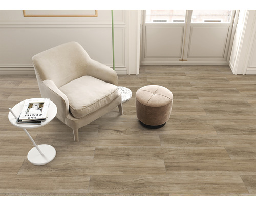 Cameră luminoasă cu fotoliu, taburet și gresie cu aspect de lemn