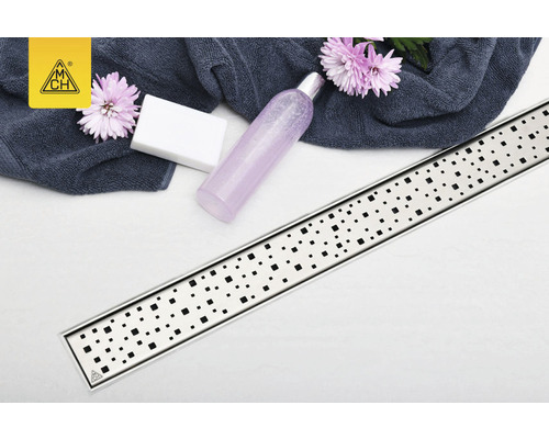 Scenă de baie cu rigolă de duș, săpun, prosop și flacon cosmetic