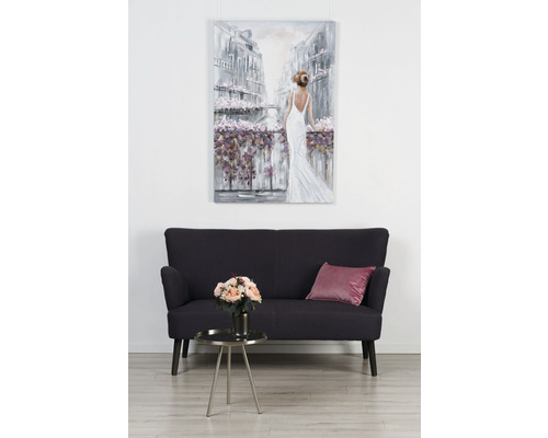 Interior decorativ cu canapea, măsuță laterală, flori artificiale și un tablou cu o femeie.