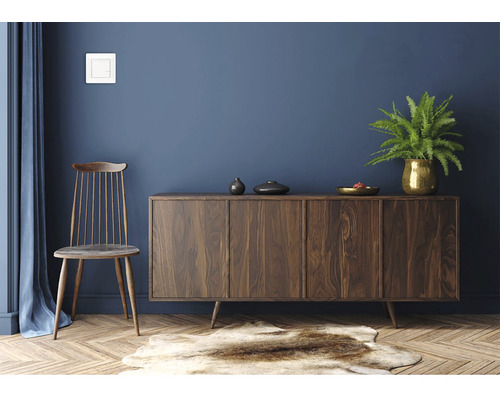 Living cu comodă din lemn, scaun și plantă de interior în vază aurie.