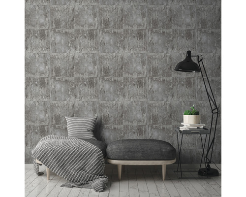 Tapetă gri cu aspect de cărămidă într-un living elegant, cu lampă, taburet și perne.