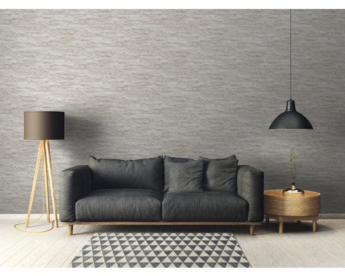 Cameră de zi cu canapea, lampadar și corp de iluminat suspendat în fața unui perete texturat