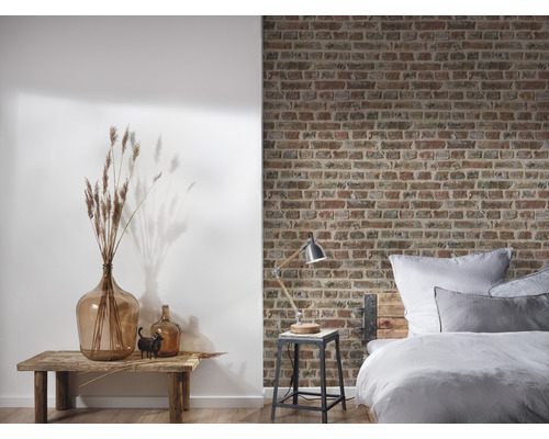 Dormitor cu pat în fața unui perete de cărămidă și decorațiuni pe o masă din lemn