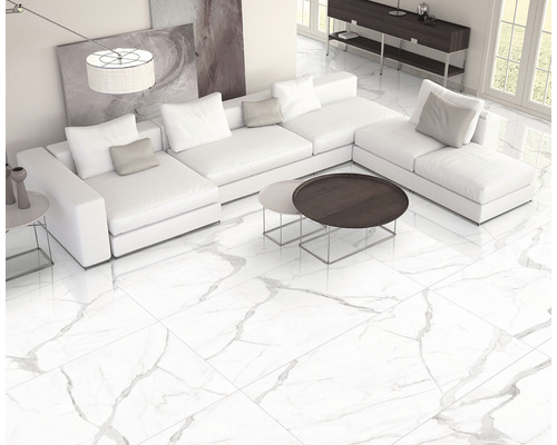 Cameră de zi luminoasă cu gresie de marmură albă, canapea de colț albă și măsuțe de cafea.